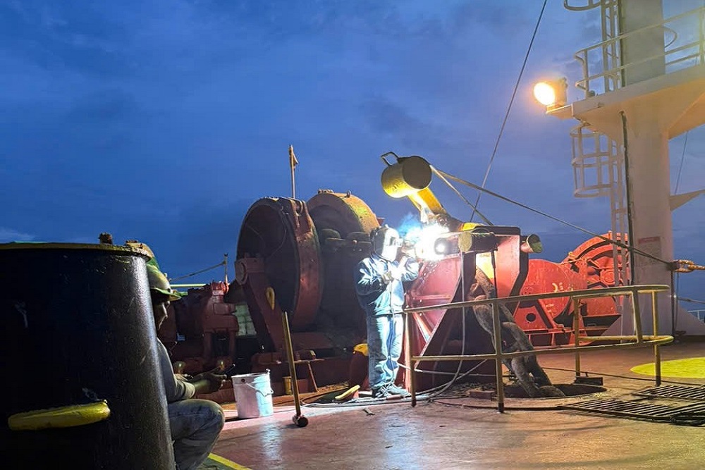 Welder carrying out repair work beside a vessel windlass