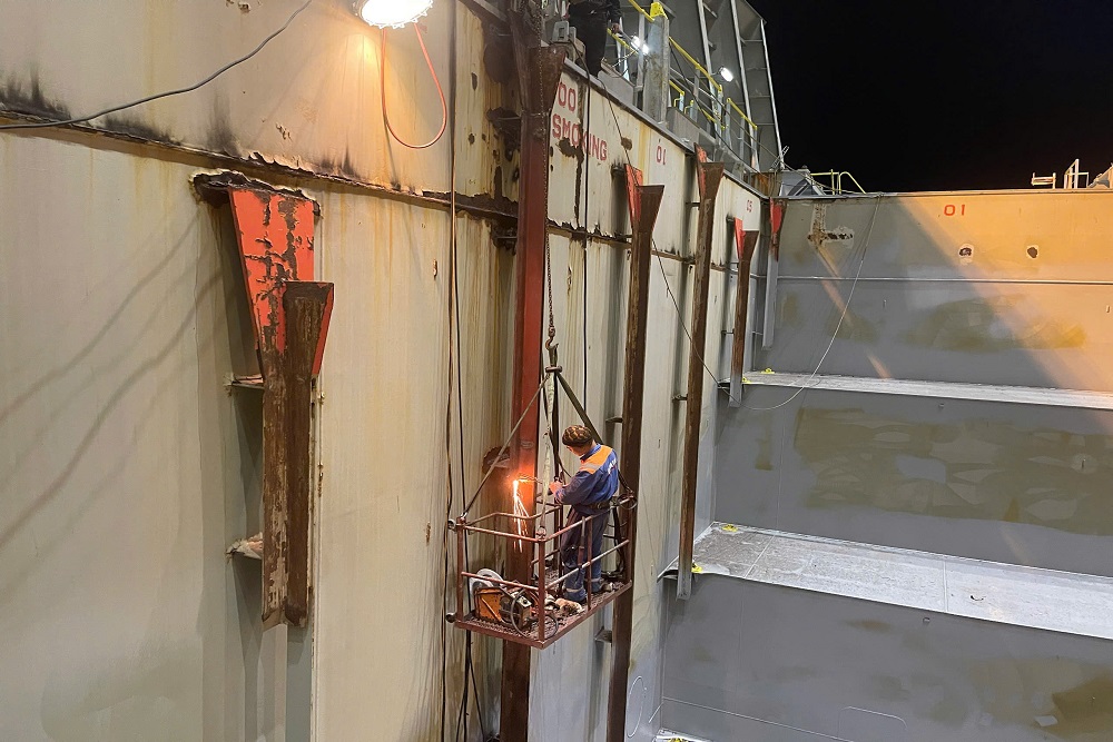 Technician carrying out cell guide repair inside a cargo hold