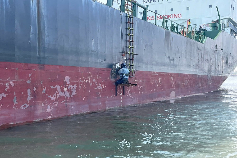 A welder welding load line marks on a vessel’s side shell