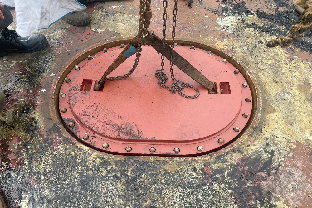 Newly fabricated bolted tank manhole cover being lifted into position