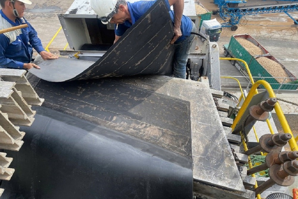 Technicians preparing a shipboard rubber conveyor belt for splicing
