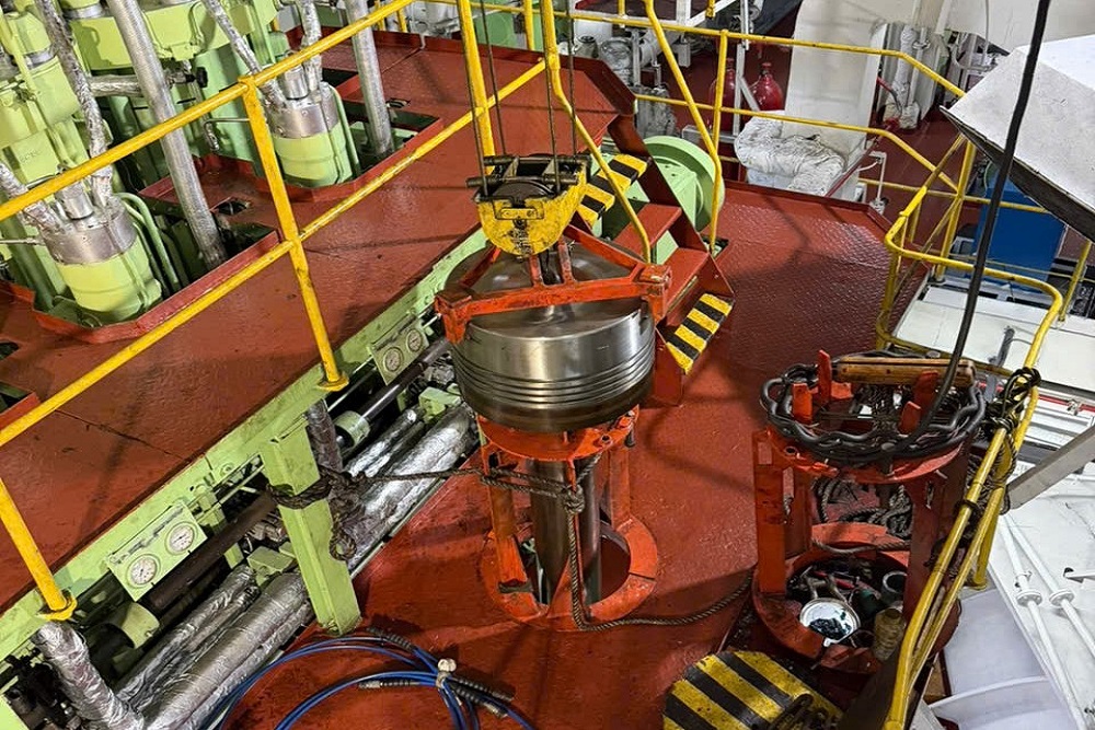 Main engine piston lifted by an engine room crane for onboard overhaul